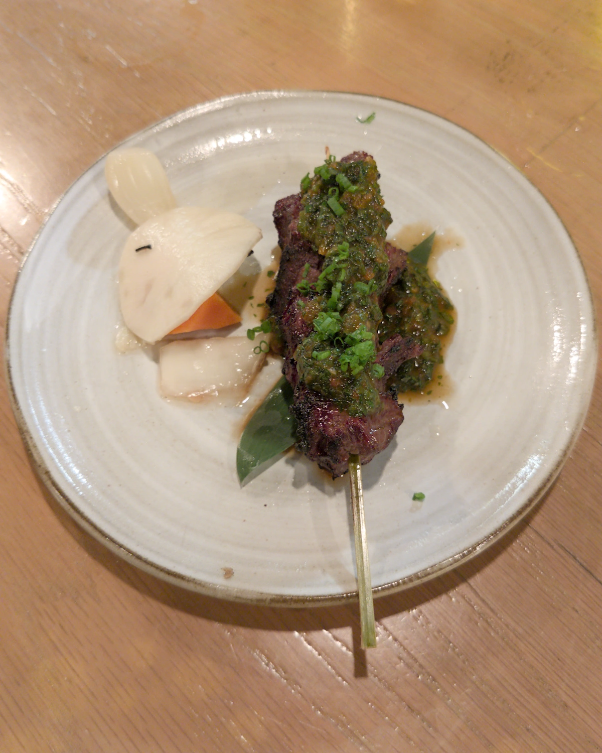 A Japanese beef skewer on a round white plate