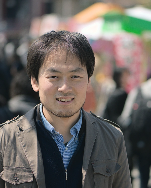 A middle aged Japanese man smiles at the camera