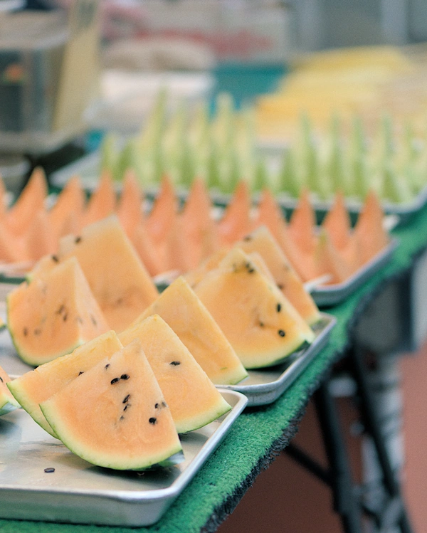 Yellow, orange, and green melon slices on metal trays