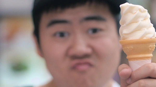 Soft serve ice cream cone held by a person who's face is blurry in the background