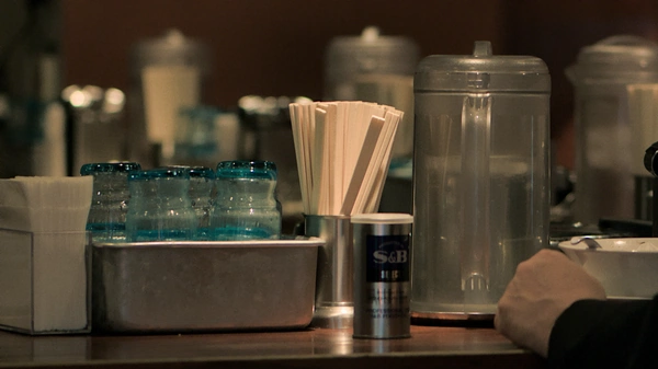 A Counter at a japanese restaurant with chopsticks, water glasses and spice container