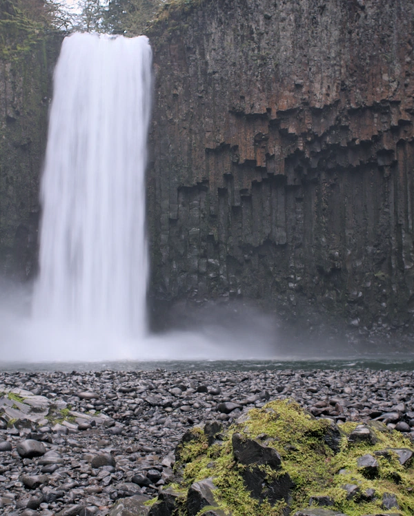 A waterfall flowing into a pool surrounded by a columnar basalt amphitheater