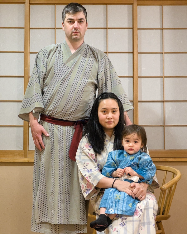 A father, mother and son dressed in yukata posing seriously for a photo